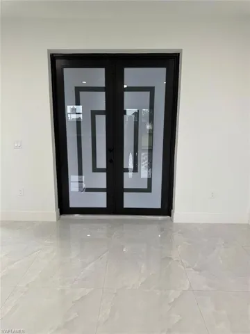 Empty room with french doors and light tile flooring