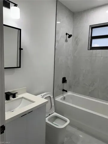 Full bathroom featuring tile flooring, vanity, toilet, and tiled shower / bath combo