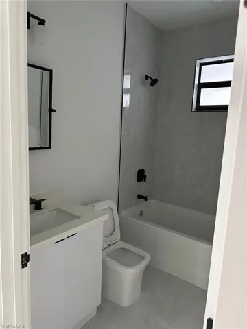 Full bathroom featuring tile floors, tiled shower / bath, vanity, and toilet