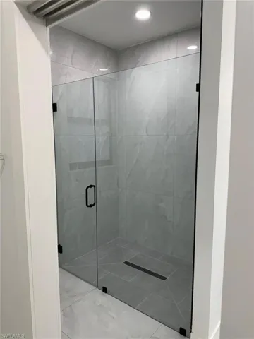 Bathroom featuring a shower with door and tile flooring