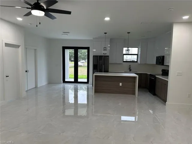 Kitchen featuring black appliances, a center island, ceiling fan, and light tile floors