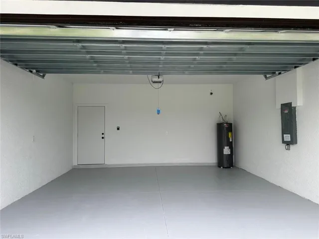 Garage featuring a garage door opener and electric water heater
