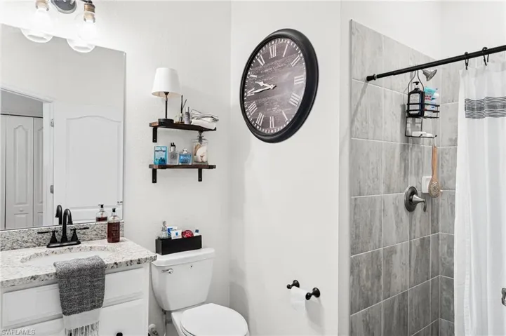 Full bath with tiled shower, vanity, and toilet