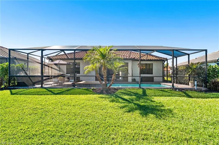 Rear view of house with a yard, glass enclosure, and an outdoor pool