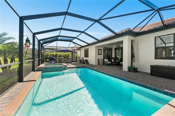 View of swimming pool with glass enclosure, a pool with connected hot tub, a patio, and a ceiling fan