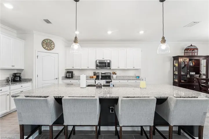 Kitchen with stainless steel appliances, white cabinets, visible vents, and ornamental molding