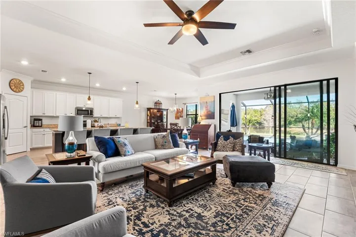 Living area featuring visible vents, a raised ceiling, crown molding, and light tile patterned flooring