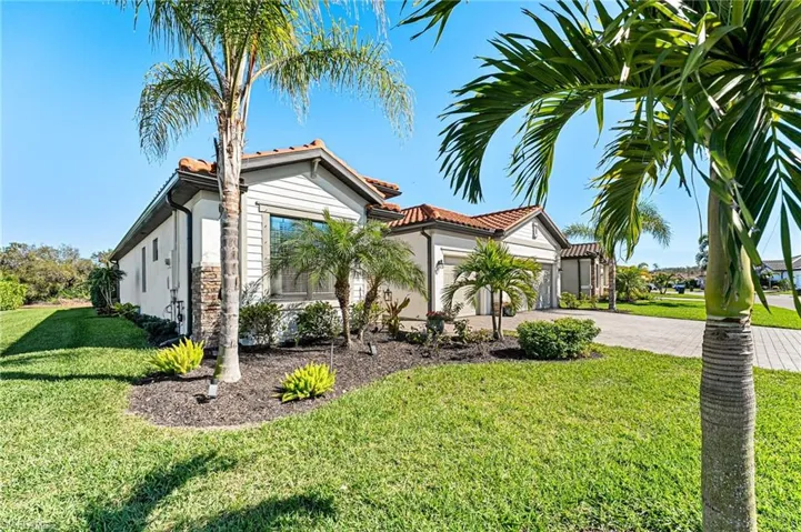 View of front of house featuring an attached garage, driveway, a front yard, and a tiled roof