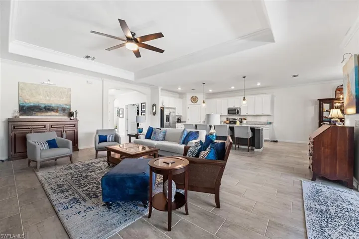 Living room with ornamental molding, a tray ceiling, visible vents, and arched walkways