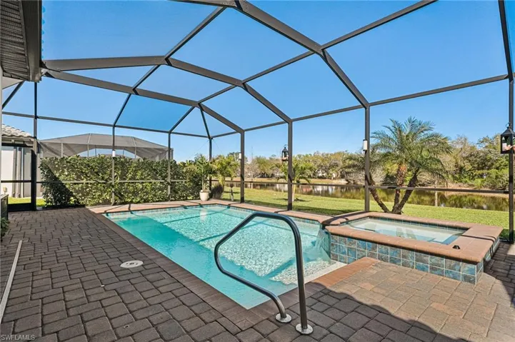 View of pool with a lanai, a pool with connected hot tub, and a patio