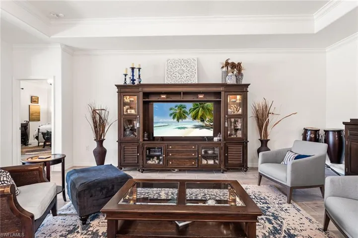 Living area with ornamental molding, a tray ceiling, and baseboards
