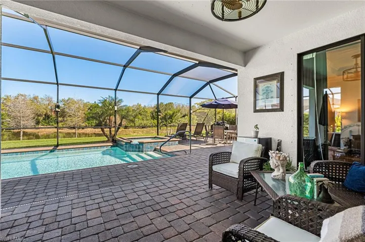 View of swimming pool featuring a patio area, glass enclosure, and a pool with connected hot tub