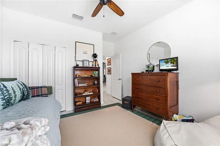 Carpeted bedroom with a ceiling fan, a closet, and visible vents