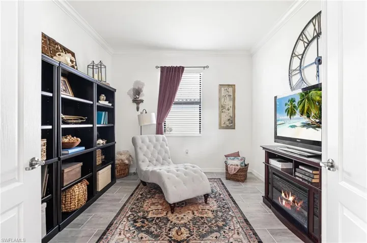 Living area with ornamental molding, wood tiled floor, and baseboards