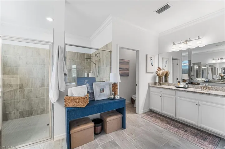 Full bath with ornamental molding, a stall shower, visible vents, and vanity