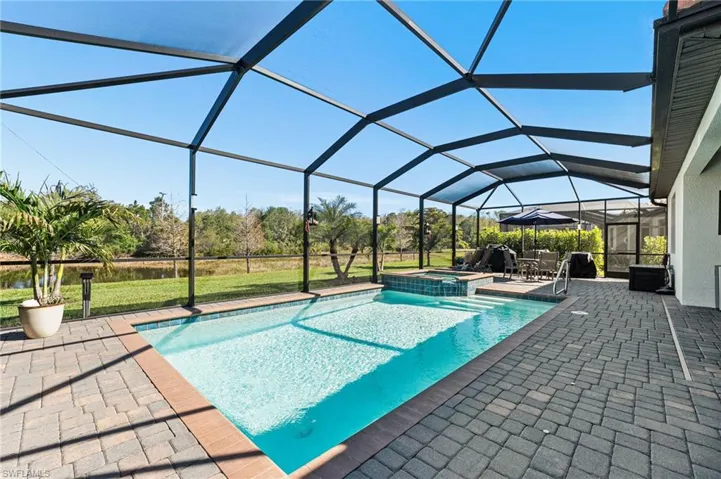 View of pool with glass enclosure, a patio area, and a pool with connected hot tub