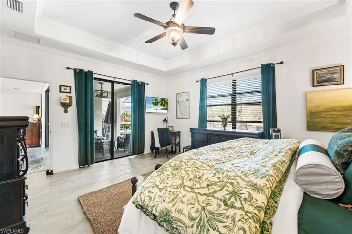 Bedroom with ornamental molding, a tray ceiling, access to outside, and visible vents