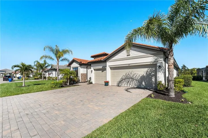 View of front facade featuring a tile roof, an attached garage, decorative driveway, a front yard, and stucco siding
