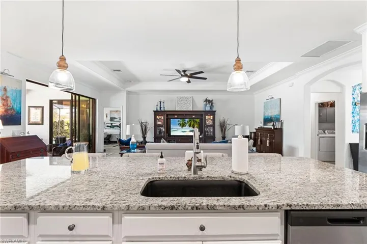 Kitchen with washer / clothes dryer, open floor plan, a tray ceiling, stainless steel dishwasher, and a sink