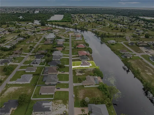 Aerial view of property and surrounding area featuring a nearby body of water and nearby suburban area