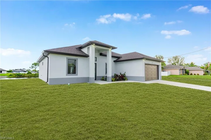 Prairie-style home featuring concrete driveway, stucco siding, and a front lawn