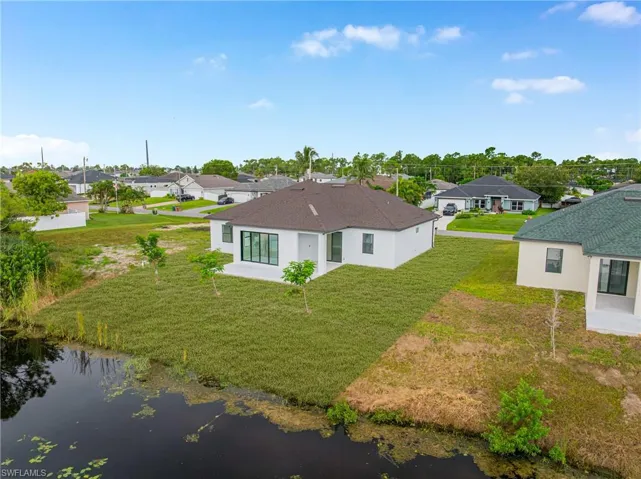 Rear view of house with a residential view, a patio area, a water view, and a yard