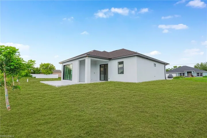 Rear view of house featuring a patio area, a yard, and stucco siding
