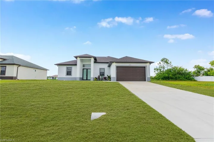 Prairie-style house with concrete driveway, a front lawn, stucco siding, and a garage