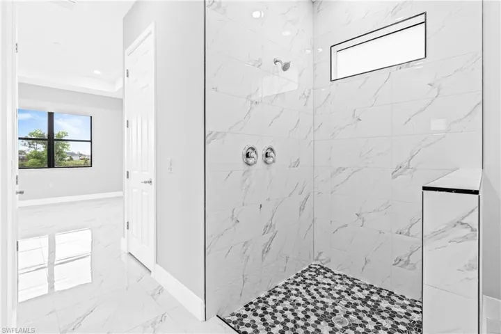 Bathroom with a marble finish shower, light marble finish floors, and recessed lighting