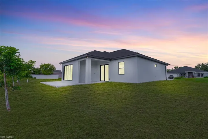 Back of property with a patio area, a yard, and stucco siding