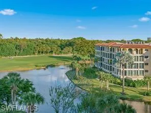 Mediterranean-style building featuring a tiled roof and multiple levels of windows, situated alongside a water feature with a golf course beyond