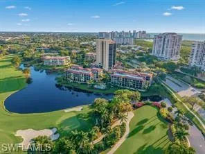 Elevated perspective showcasing a golf course, a prominent water feature, and multiple residential buildings