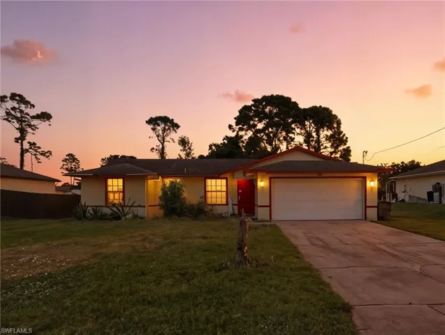 Single-story residence featuring a paved driveway, attached garage, grid-pattern windows, and exterior sconce lighting