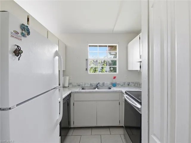 Kitchen with freestanding refrigerator, electric stove, light countertops, light tile patterned floors, and dishwasher