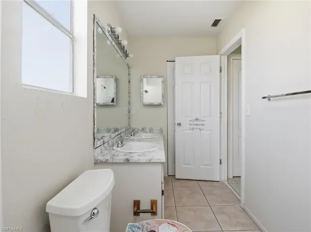 Bathroom with double vanity and light tile patterned floors