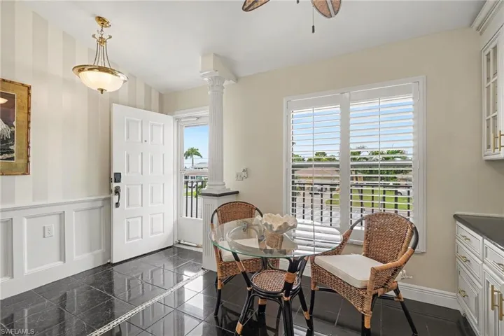 Black polished tile flooring, white wainscoting, and a paneled entry door