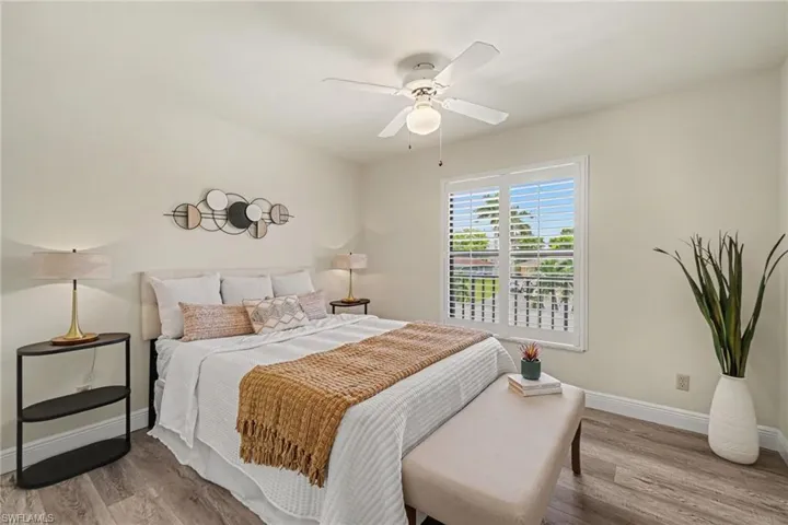 Wood-finish flooring, overhead ceiling fan, window with plantation shutters, and light-toned walls