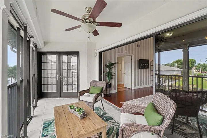 Screened patio with tile flooring and a ceiling fan, featuring double french doors