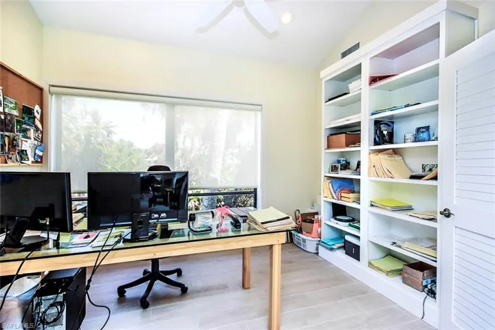 Office space featuring vaulted ceiling, light wood-type flooring, and a ceiling fan