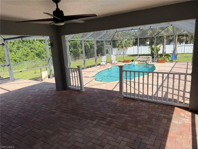 Screened-in outdoor living space featuring a ceiling fan, brick paver patio, in-ground swimming pool, and safety fencing