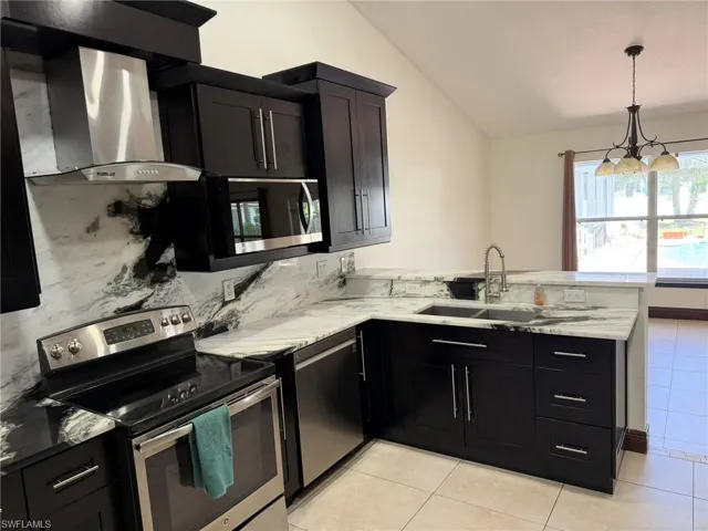 Kitchen featuring dark wood cabinetry, stainless steel appliances, and white stone countertops with integrated backsplash