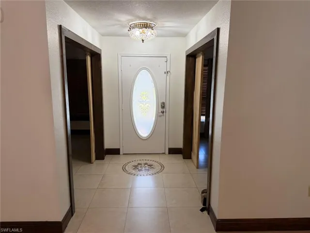Tiled entry with a decorative floor medallion, white front door with an oval-shaped stained glass insert, and a ceiling-mounted light fixture