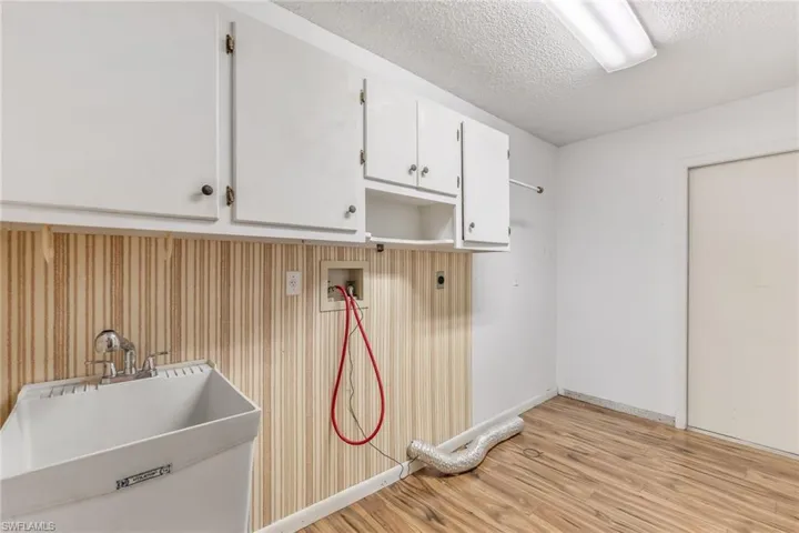 Washroom with washer hookup, electric dryer hookup, laundry tub and cabinets. Door pictured leads into the garage.