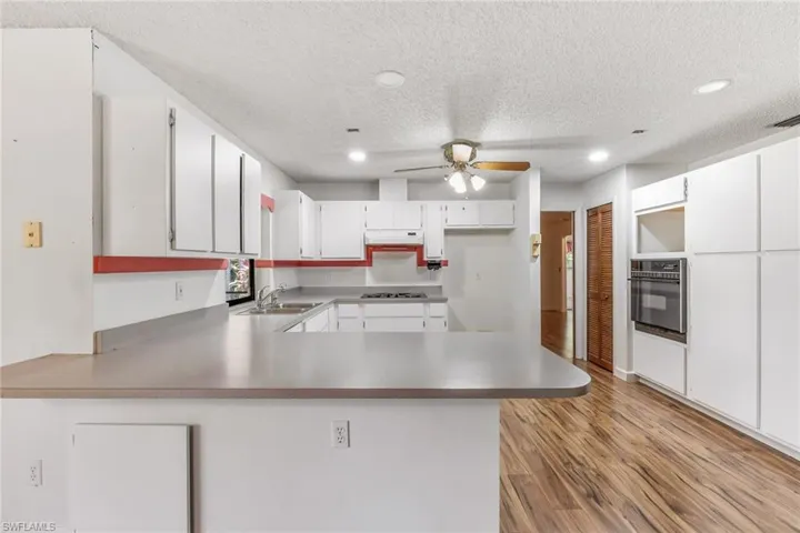 Kitchen featuring storage in the island. Vinyl wood flooring, built-in oven and bi-fold door leading to pantry