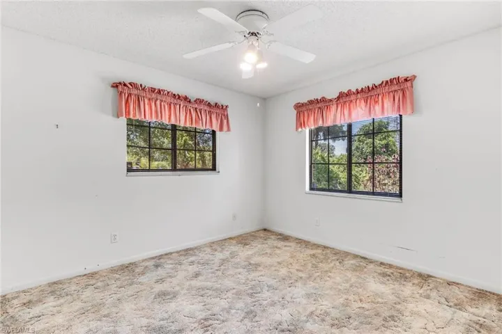 Empty room with carpet, ceiling fan, and a textured ceiling