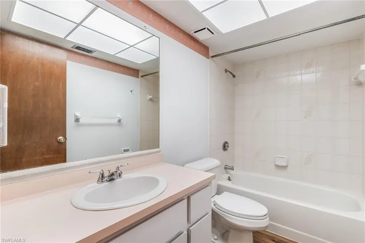 Full bathroom featuring tiled shower / bath, toilet, and vanity with extensive cabinet space.