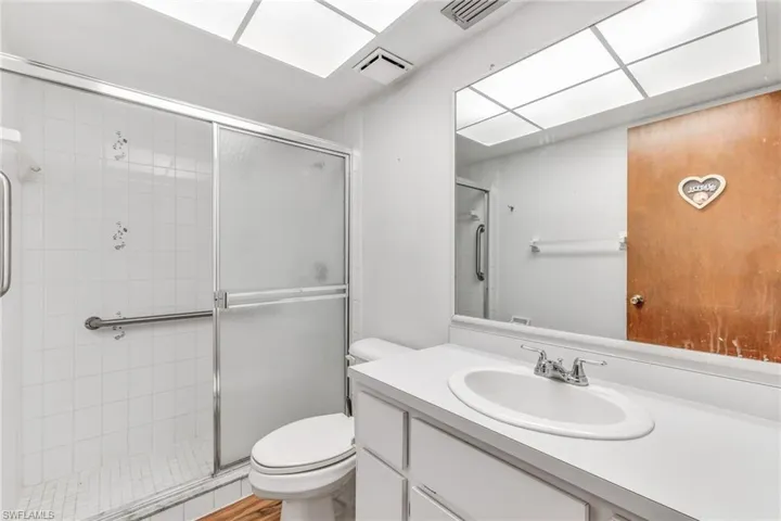 Guest bathroom featuring large shower with shower door, oversized vanity, and toilet