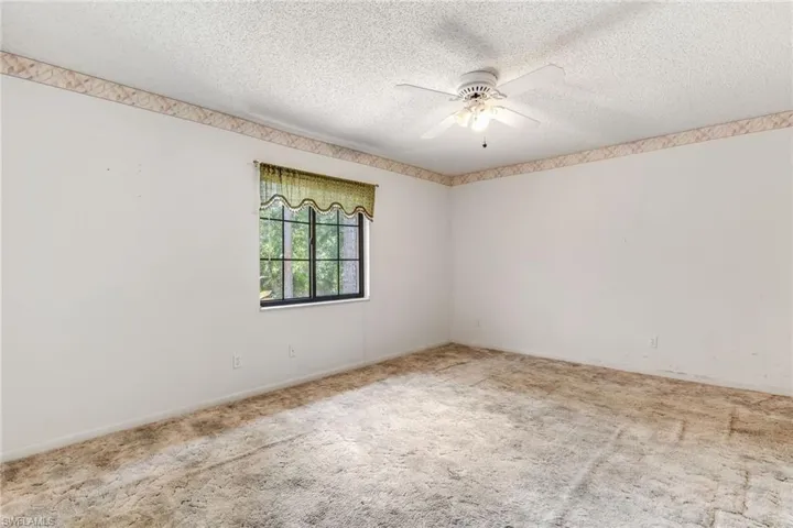 Carpeted master bedroom with ceiling fan and a textured ceiling