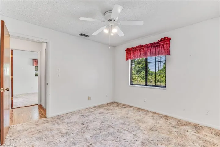 Spare room with ceiling fan. Shares a hallway into a guest bedroom and guest bathroom.