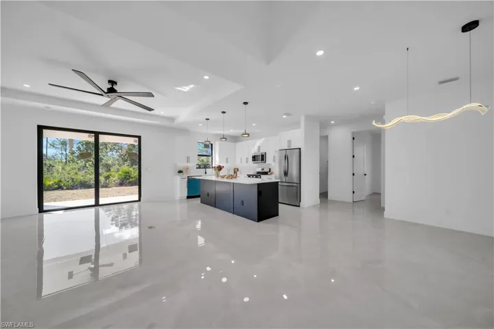 Kitchen featuring open floor plan, white cabinets, hanging light fixtures, a kitchen island, and ceiling fan